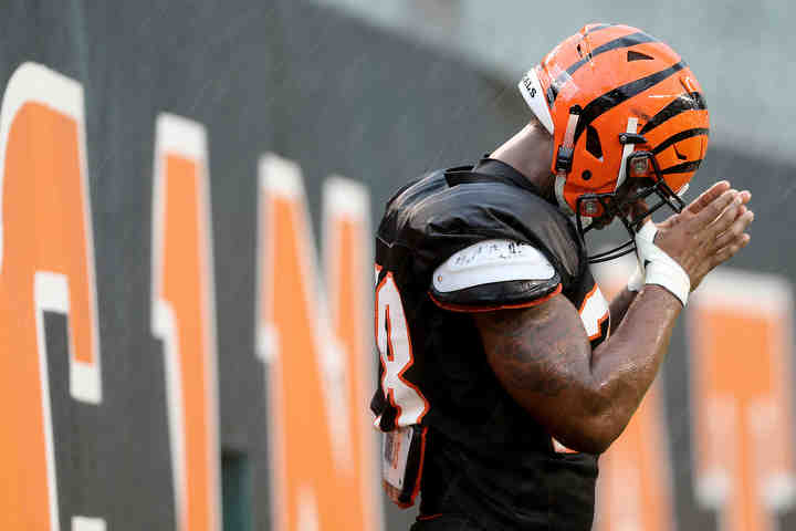 Cincinnati Bengals running back Joe Mixon (28) wipes his eyes as heavy rain falls during Cincinnati Bengals training camp practice at Paul Brown Stadium in Cincinnati.   (Kareem Elgazzar / The Cincinnati Enquirer)